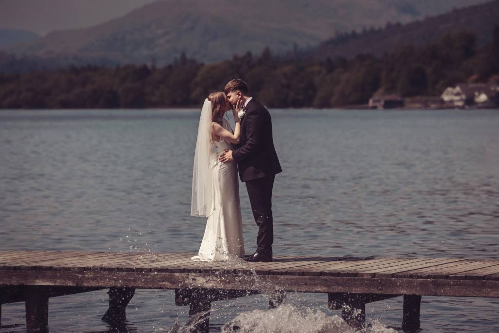 Megan and Tom, bride and groom, getting their photo by the lake
